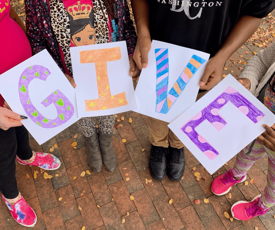 Children holding up letters that spell GIVE